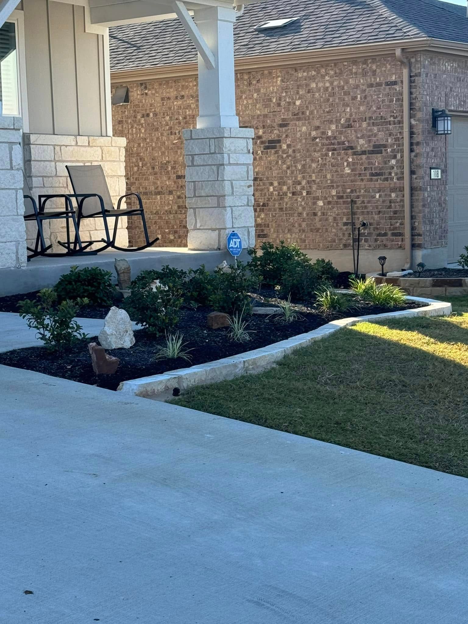 A brick house with a porch and rocking chairs in front of it.