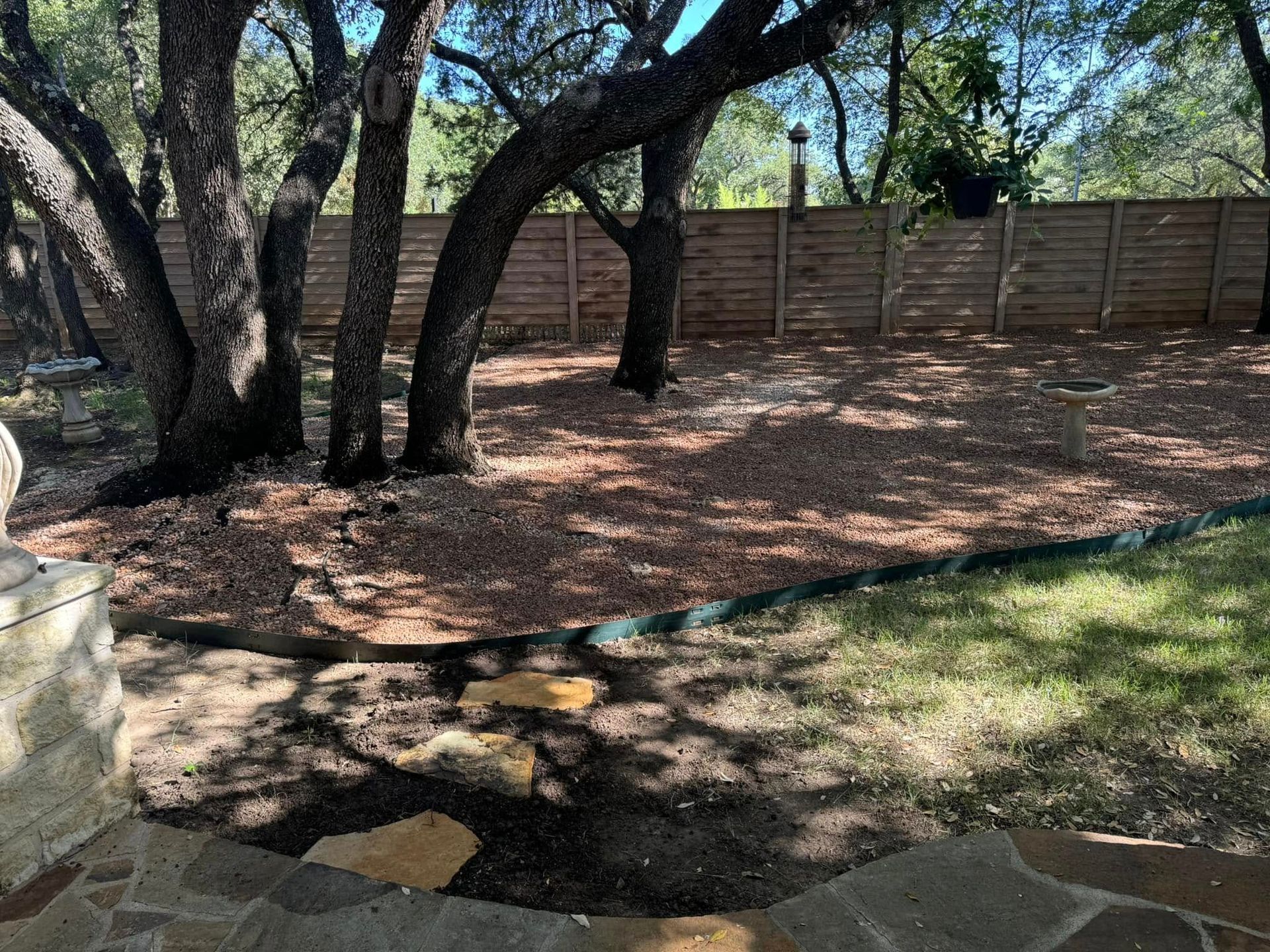 A backyard with a wooden fence and trees in the background.
