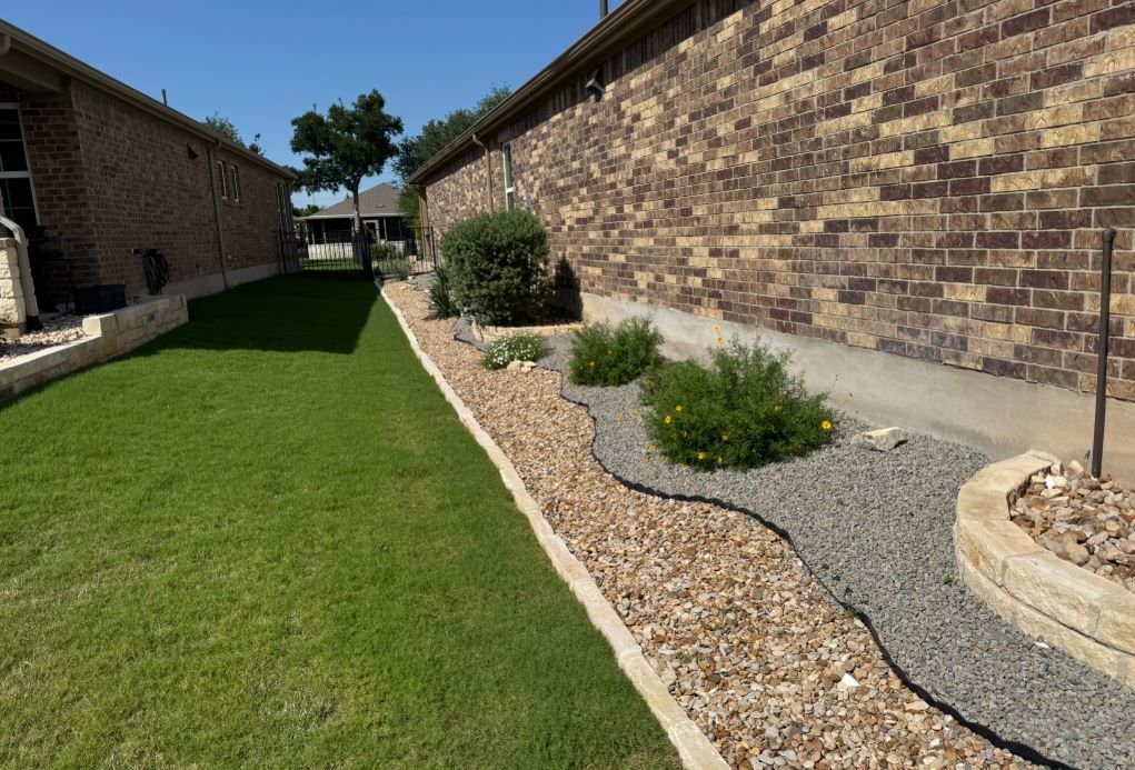 A brick wall is behind a lush green lawn