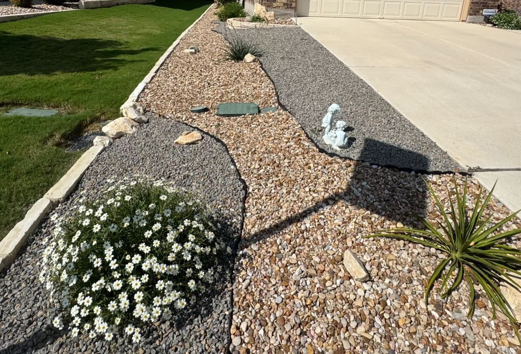 A gravel path leading to a house with flowers and plants.
