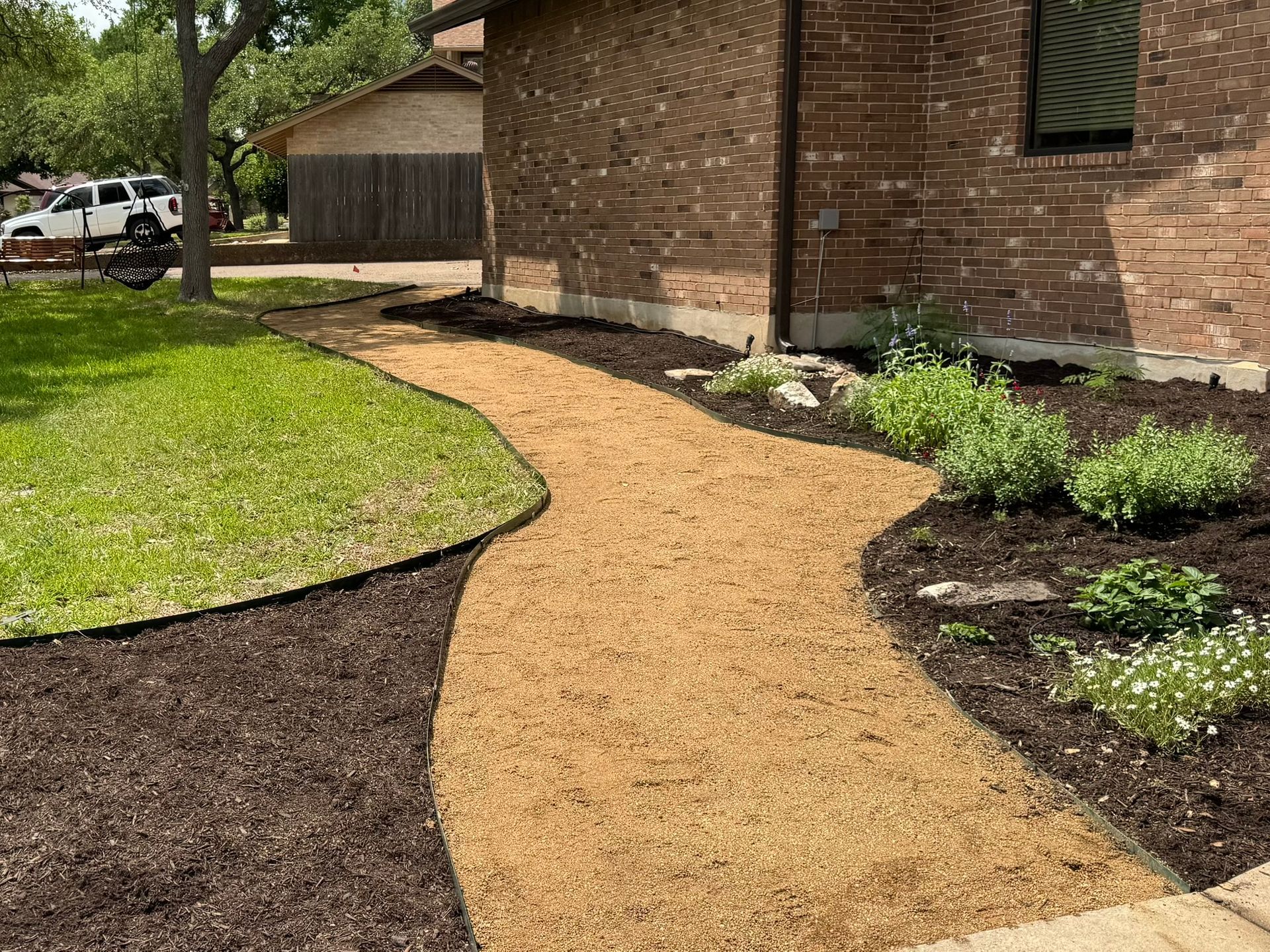 A walkway leading to a house with a brick building in the background.