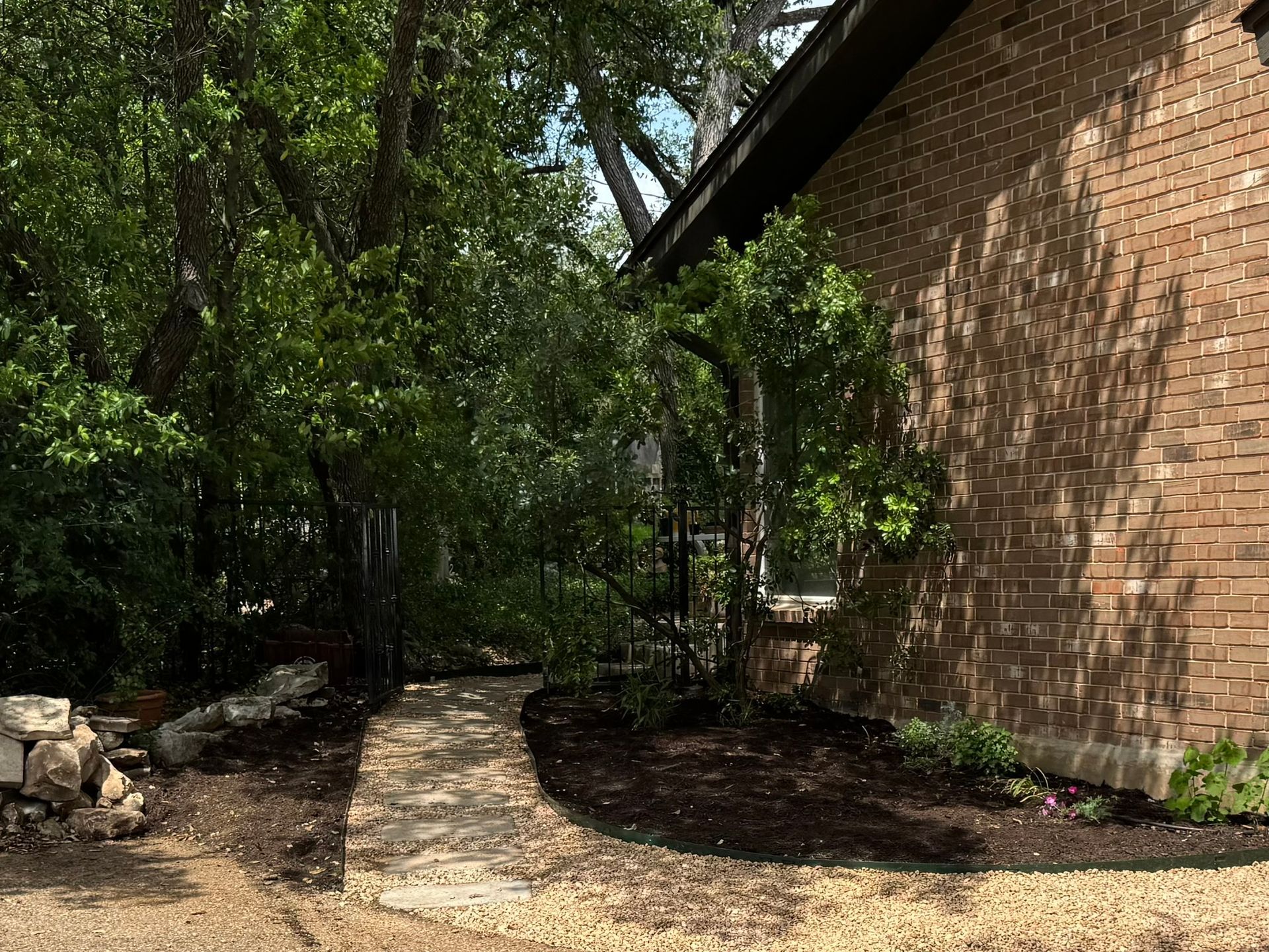 A brick house with a stone walkway leading to it surrounded by trees.