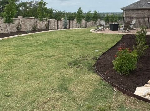 A large lawn with a patio in the background and a house in the background.