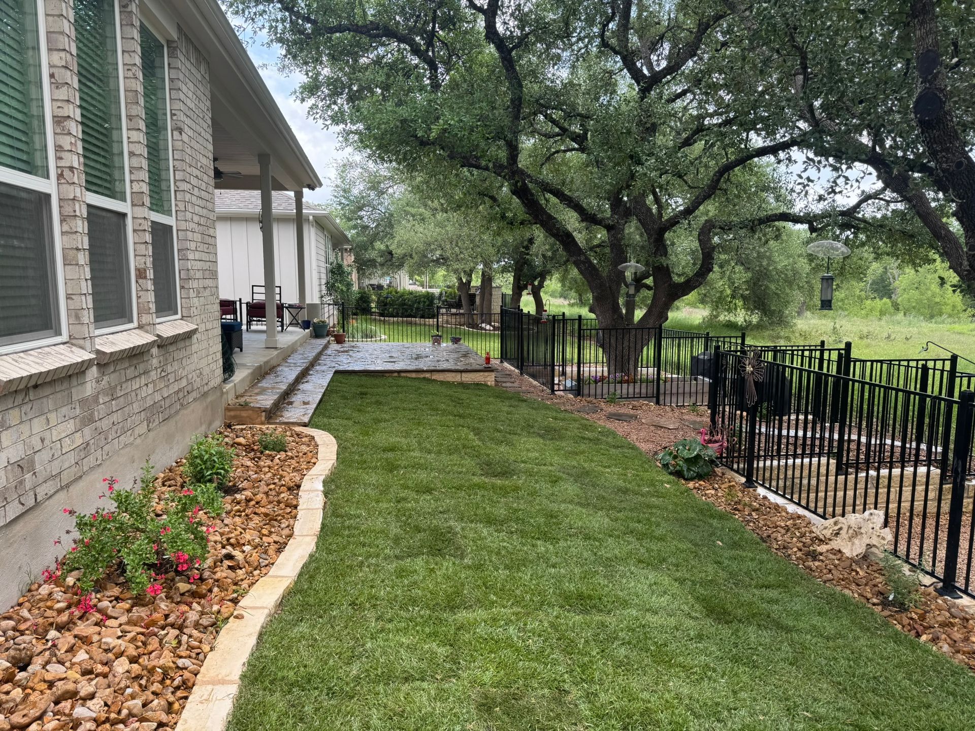 A house with a large lawn and a fence in front of it.