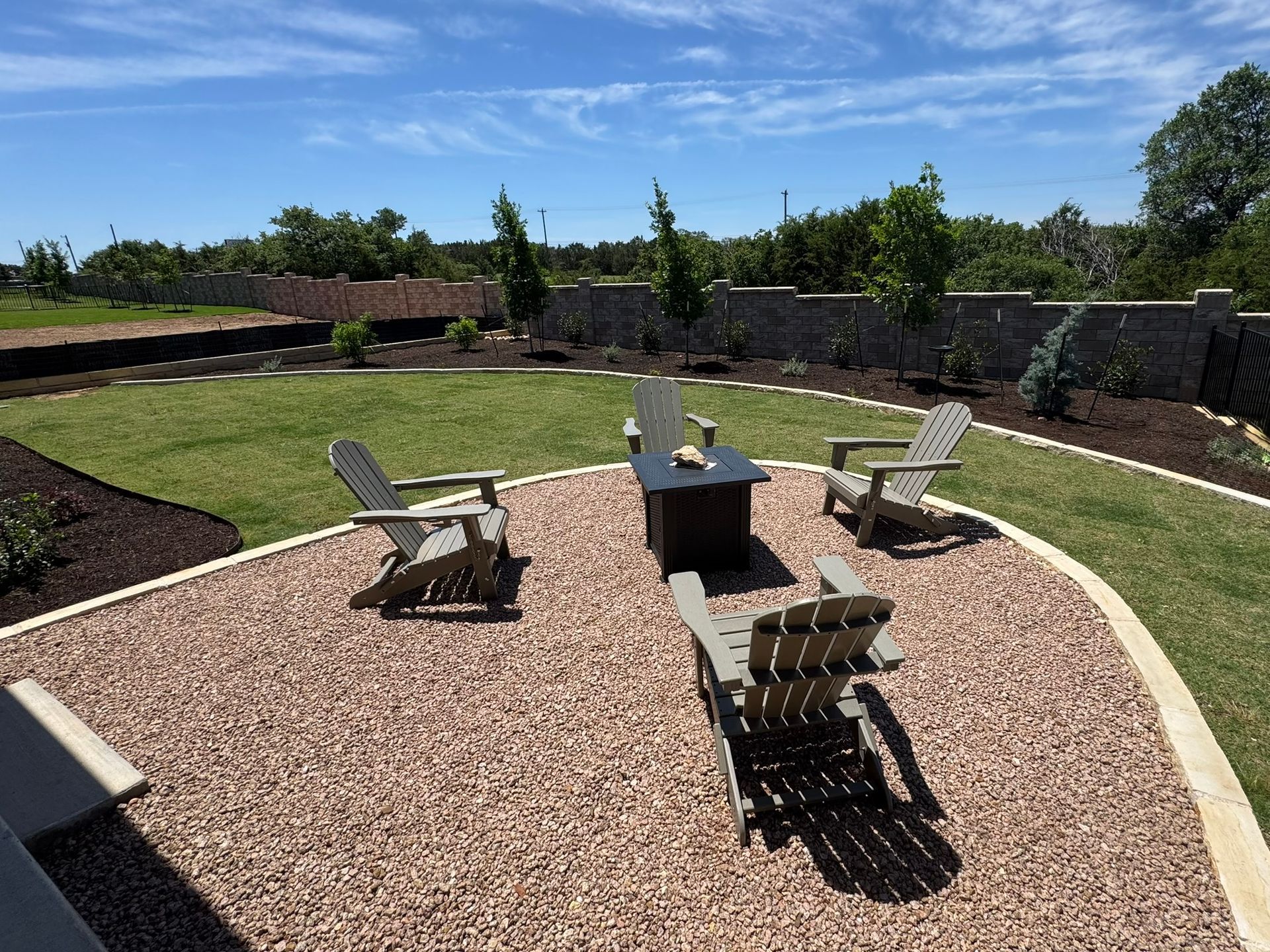 A patio with chairs and a fire pit in the middle of it.