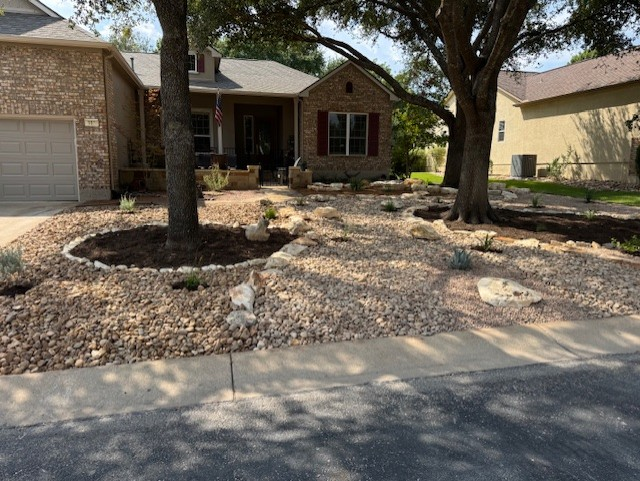 House with rock landscaping and two trees in the front yard. The sidewalk is in the foreground.