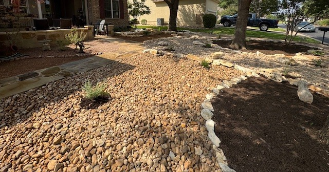 Landscaped front yard with gravel, stone edging, and small plants.
