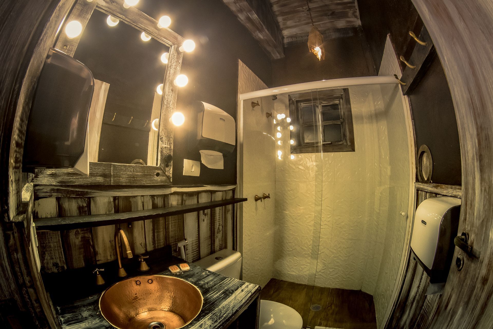 Um banheiro com pia, vaso sanitário, chuveiro e espelho.