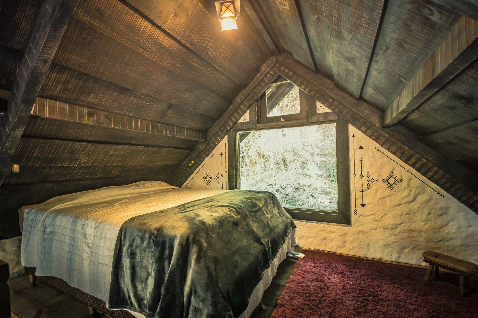 Há uma cama no sótão com janela.