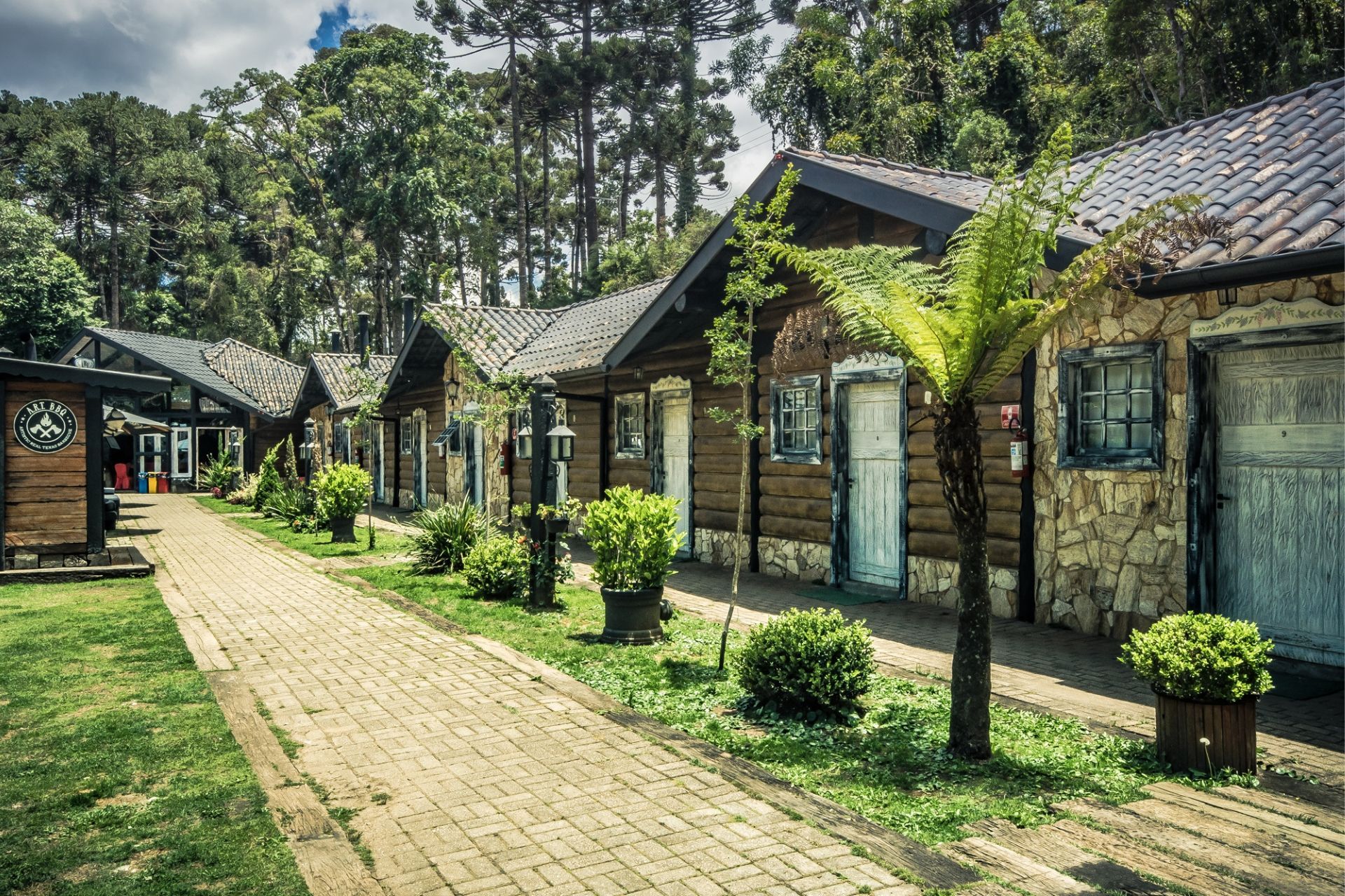 Uma fileira de cabanas de madeira lado a lado no meio de uma floresta.