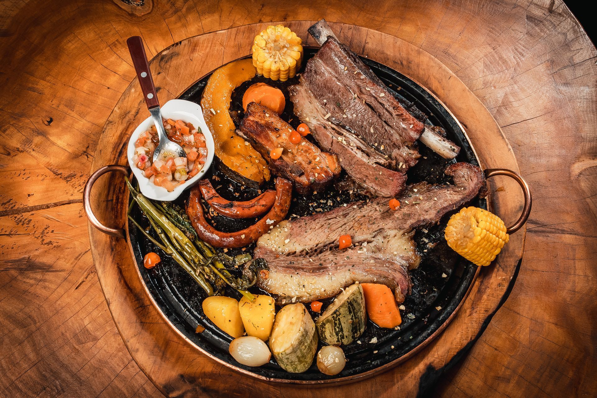 Um prato de carne e legumes sobre uma mesa de madeira.