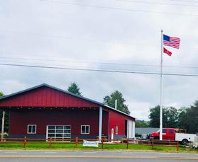 A red barn with an american flag flying in front of it