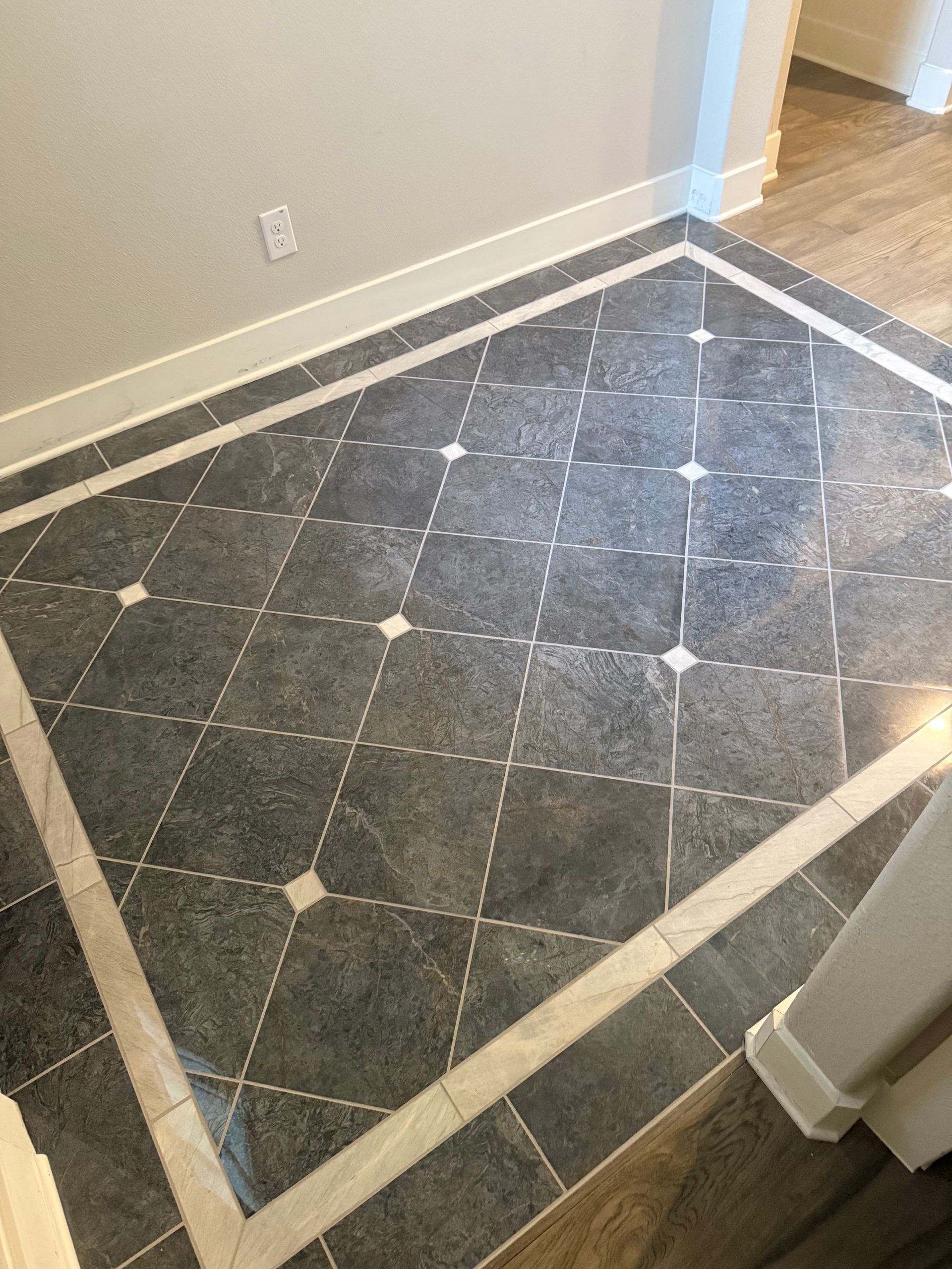 Dark gray tile floor with diamond pattern, bordered by white trim and small white accent squares.