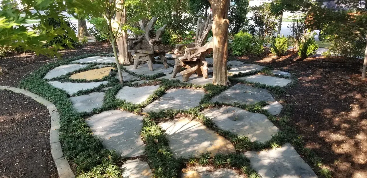 A stone walkway surrounded by trees and bushes in a garden.
