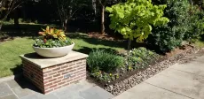 A planter is sitting on top of a brick block in a garden.