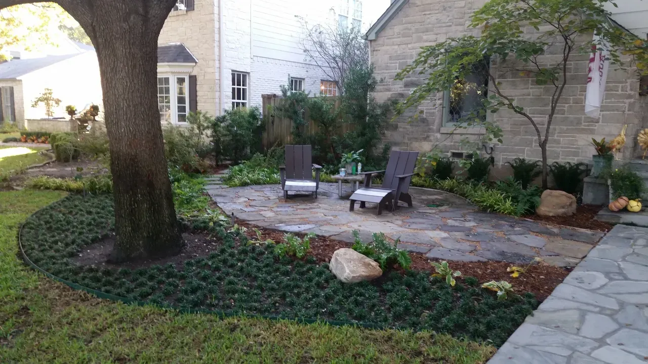 A patio with chairs and a table in front of a house.