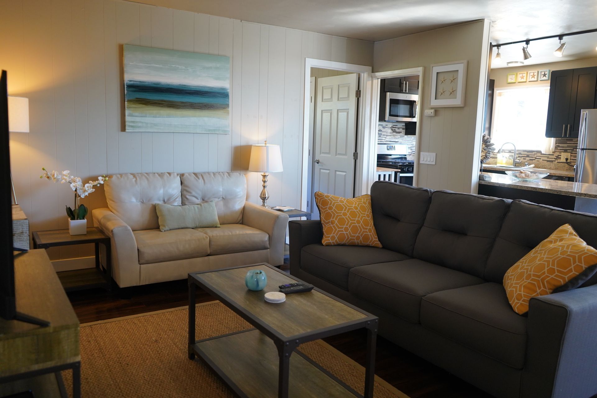 Cozy living room with beige and dark gray sofas, coffee table, wall art, and a window seat