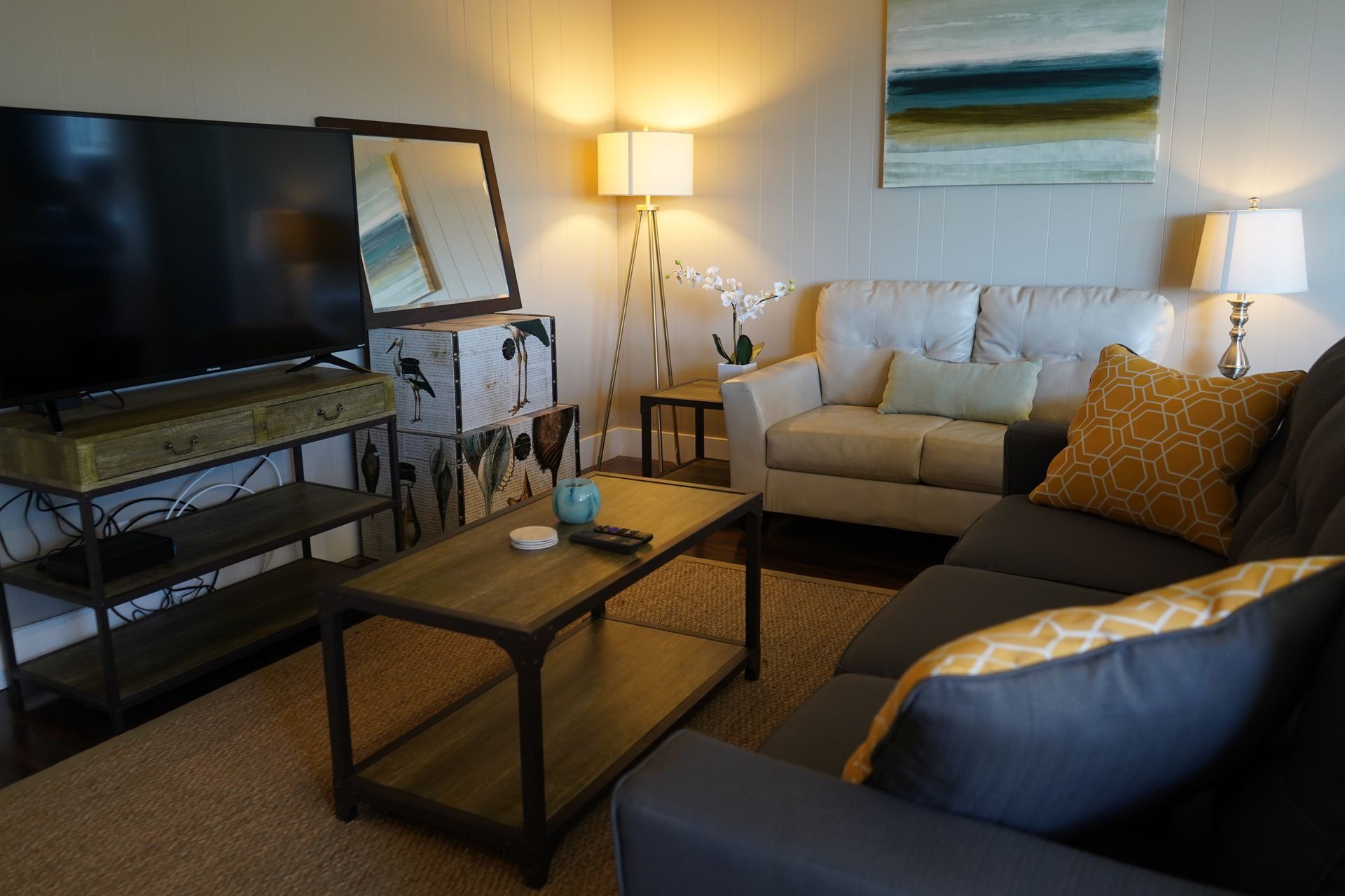 Cozy living room with beige sofa, TV, coffee table, lamps, and blue-gray armchair