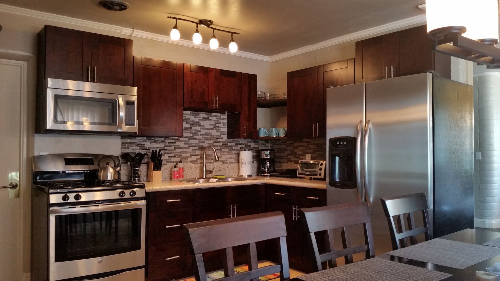 Modern kitchen with stainless steel appliances, dark wood cabinets, and a dining table in the foreground