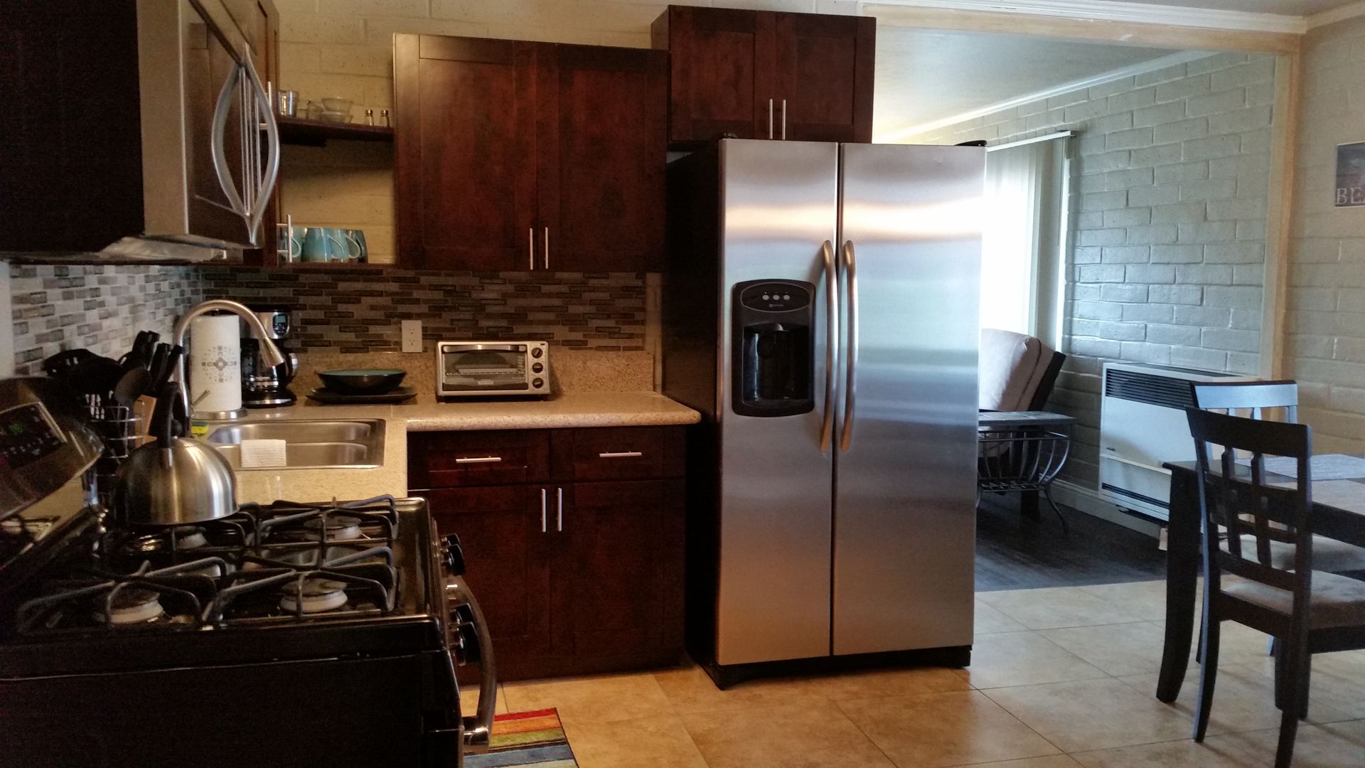 Modern kitchen with stainless steel fridge, dark wood cabinets, stove, and adjacent dining table area