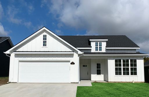 A white house with a black roof and a white garage door.