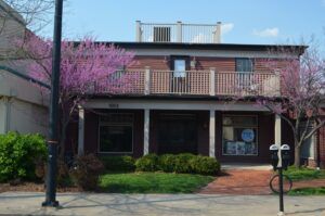 A large brick house with a balcony and a bicycle parked in front of it.