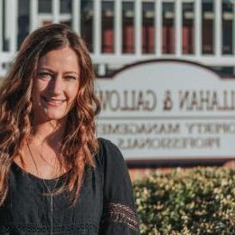 A woman stands in front of a callahan & property management sign