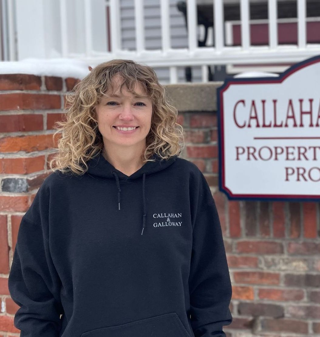 A woman in a black hoodie stands in front of a callaha property sign