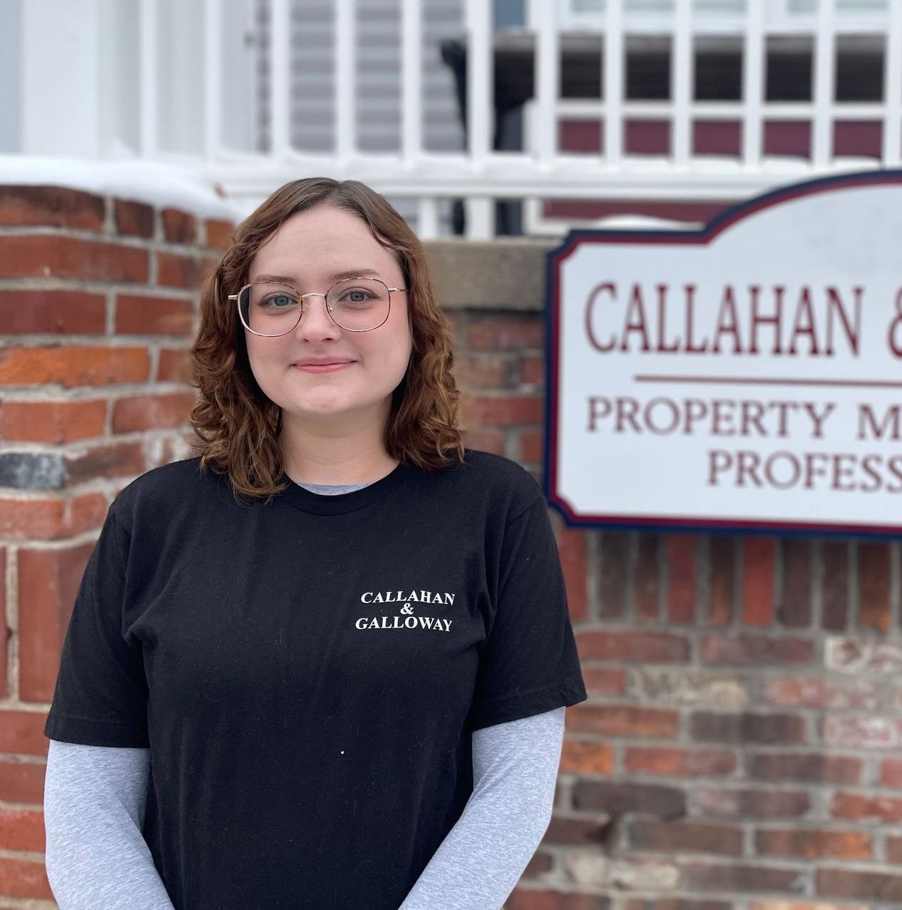 A woman is standing in front of a callahan & property management sign