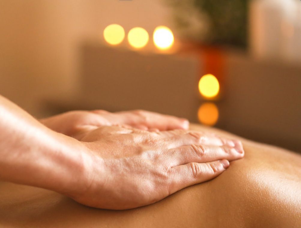 Une personne reçoit un massage dans un spa avec des bougies en arrière-plan.