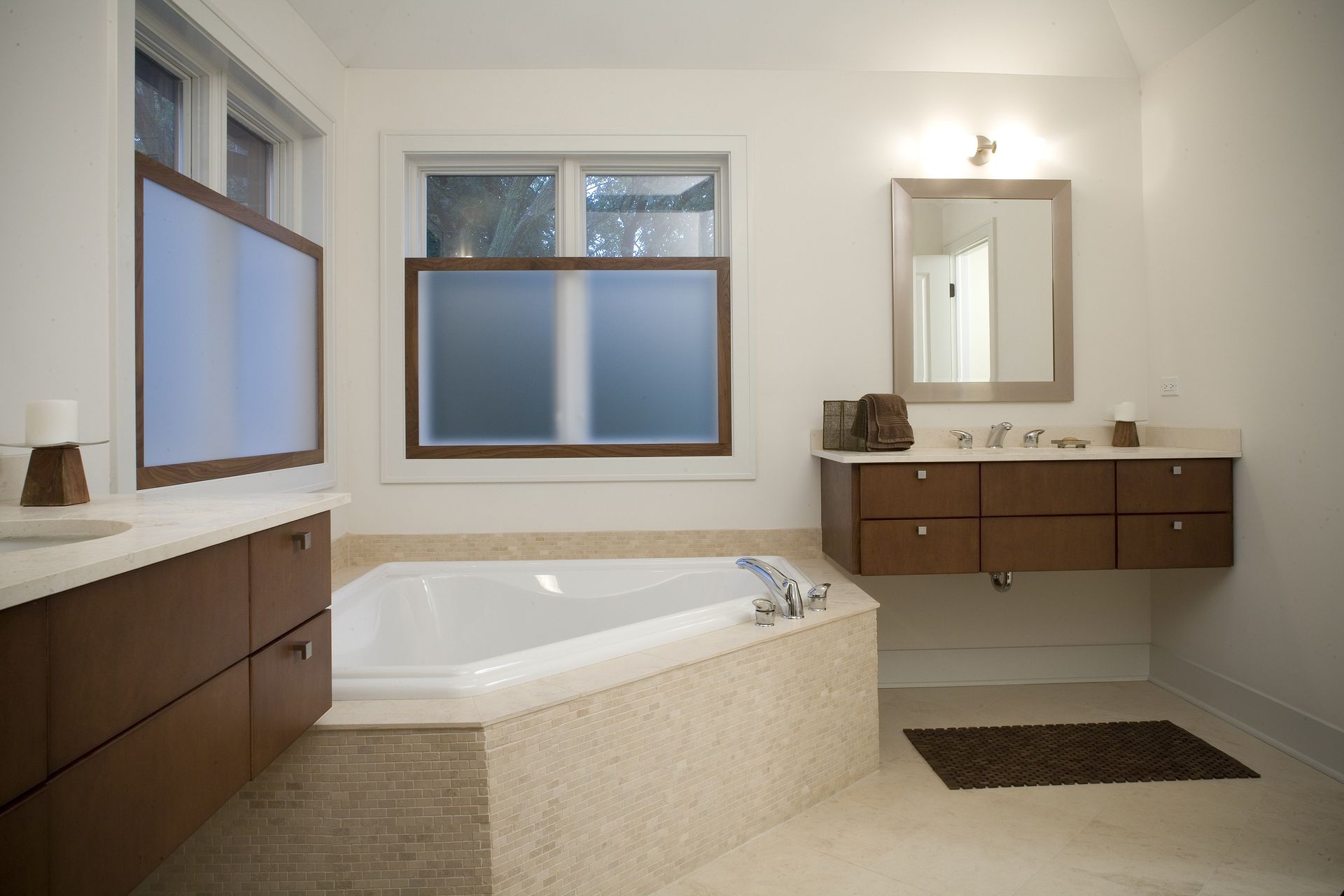 A bathroom with a tub , sink , mirror and window.