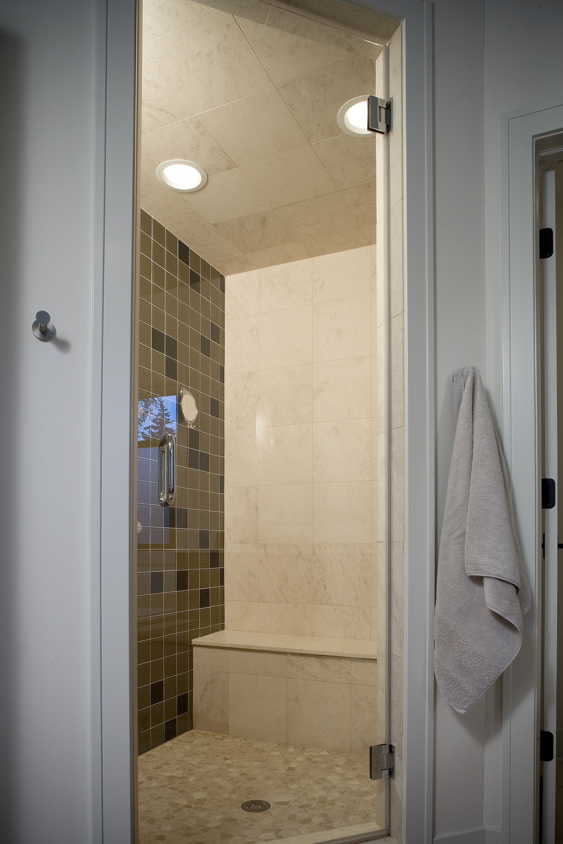 A bathroom with a glass shower door and a towel hanging on the wall.