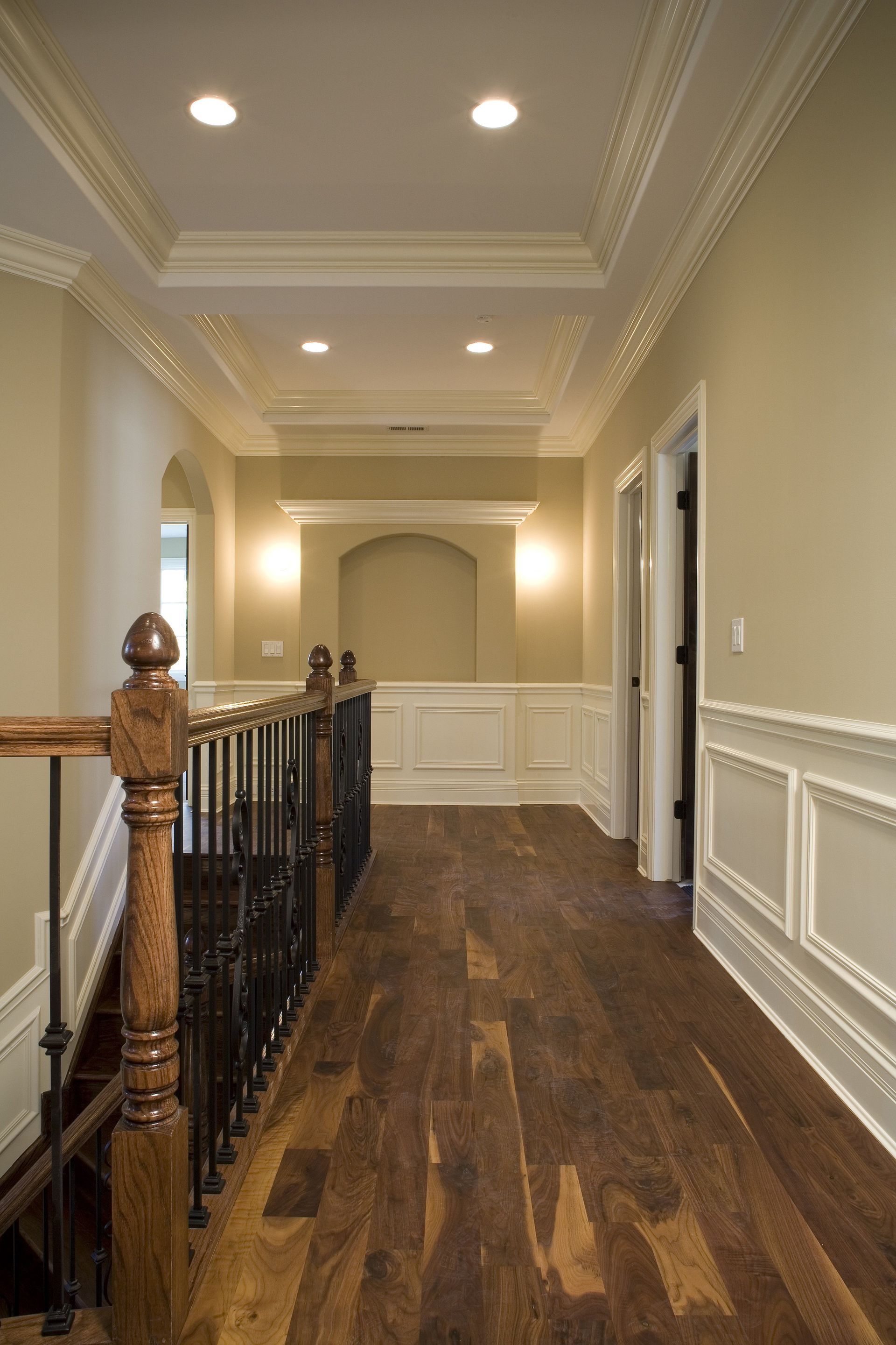 A hallway with wooden floors and stairs in a house.
