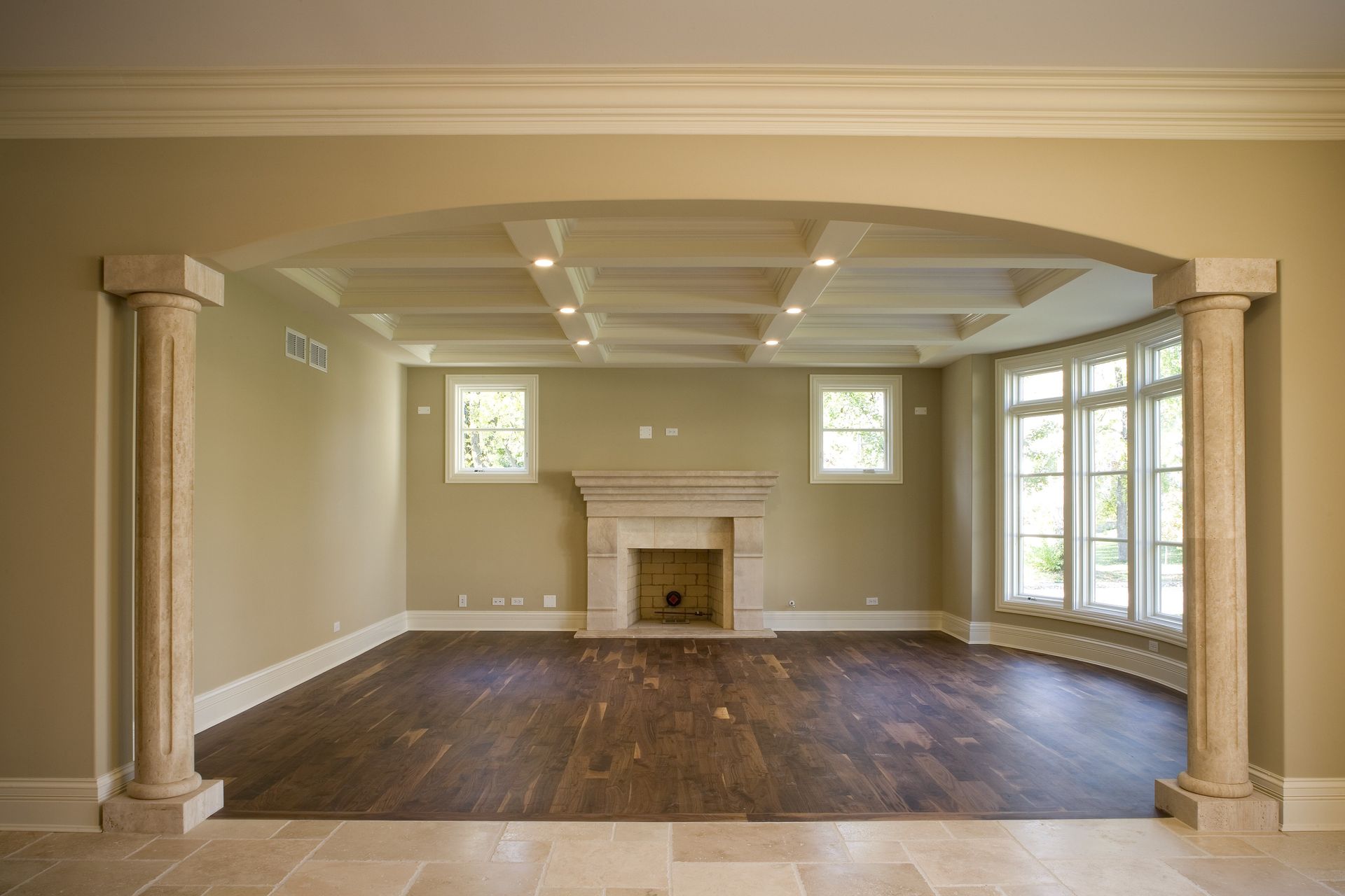 An empty living room with a fireplace and columns