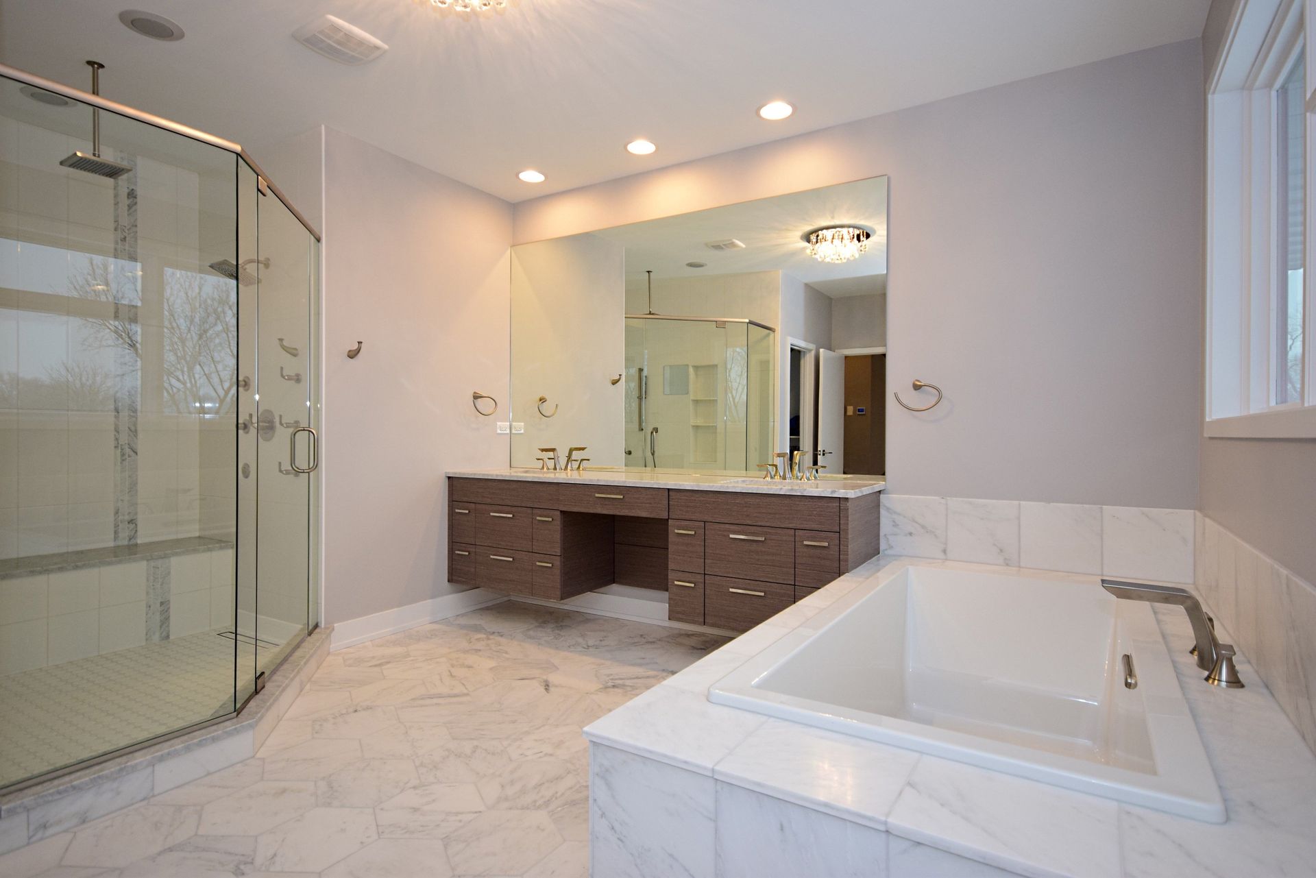 A bathroom with two sinks , a tub , a shower and a large mirror.