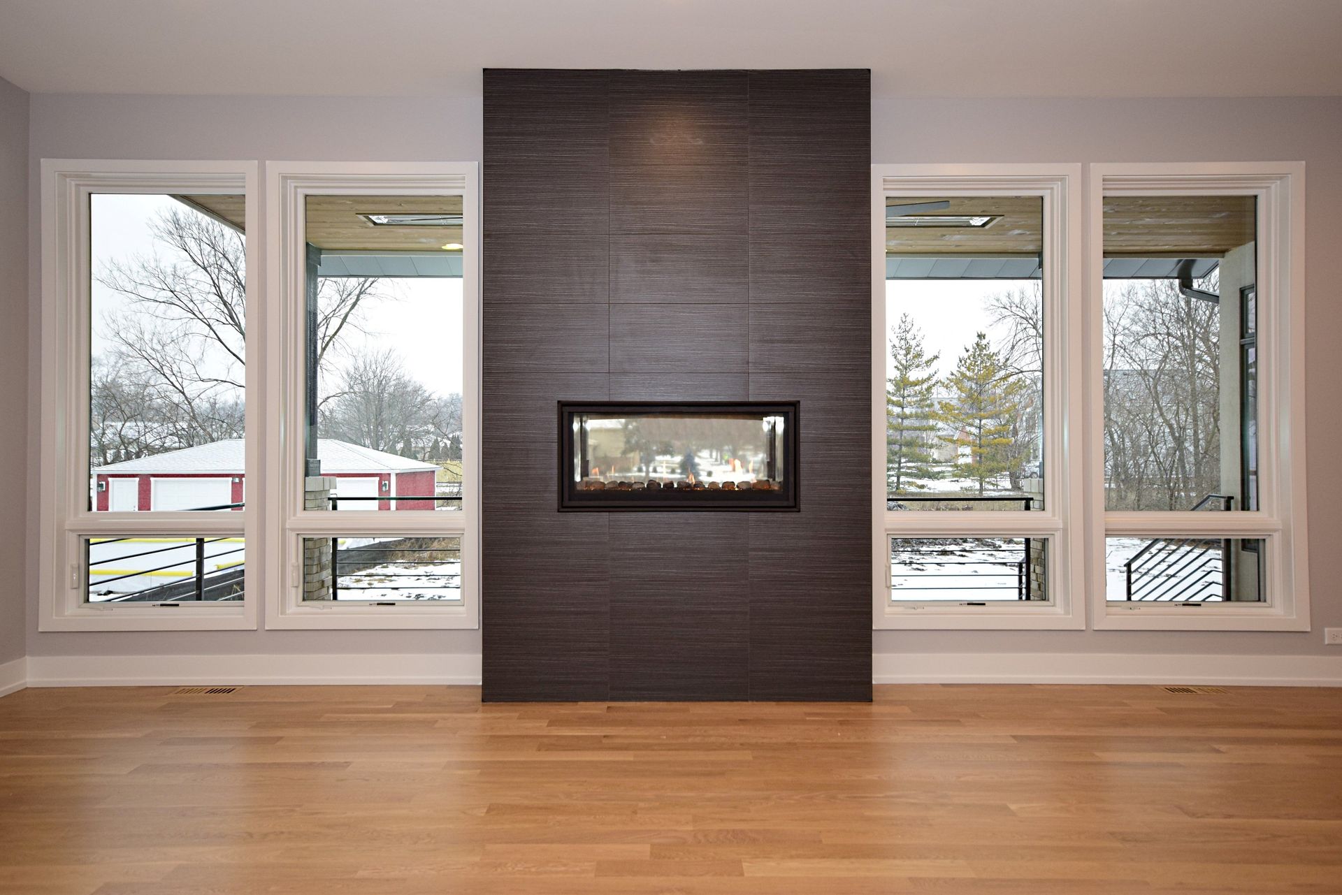 An empty living room with a fireplace and lots of windows.