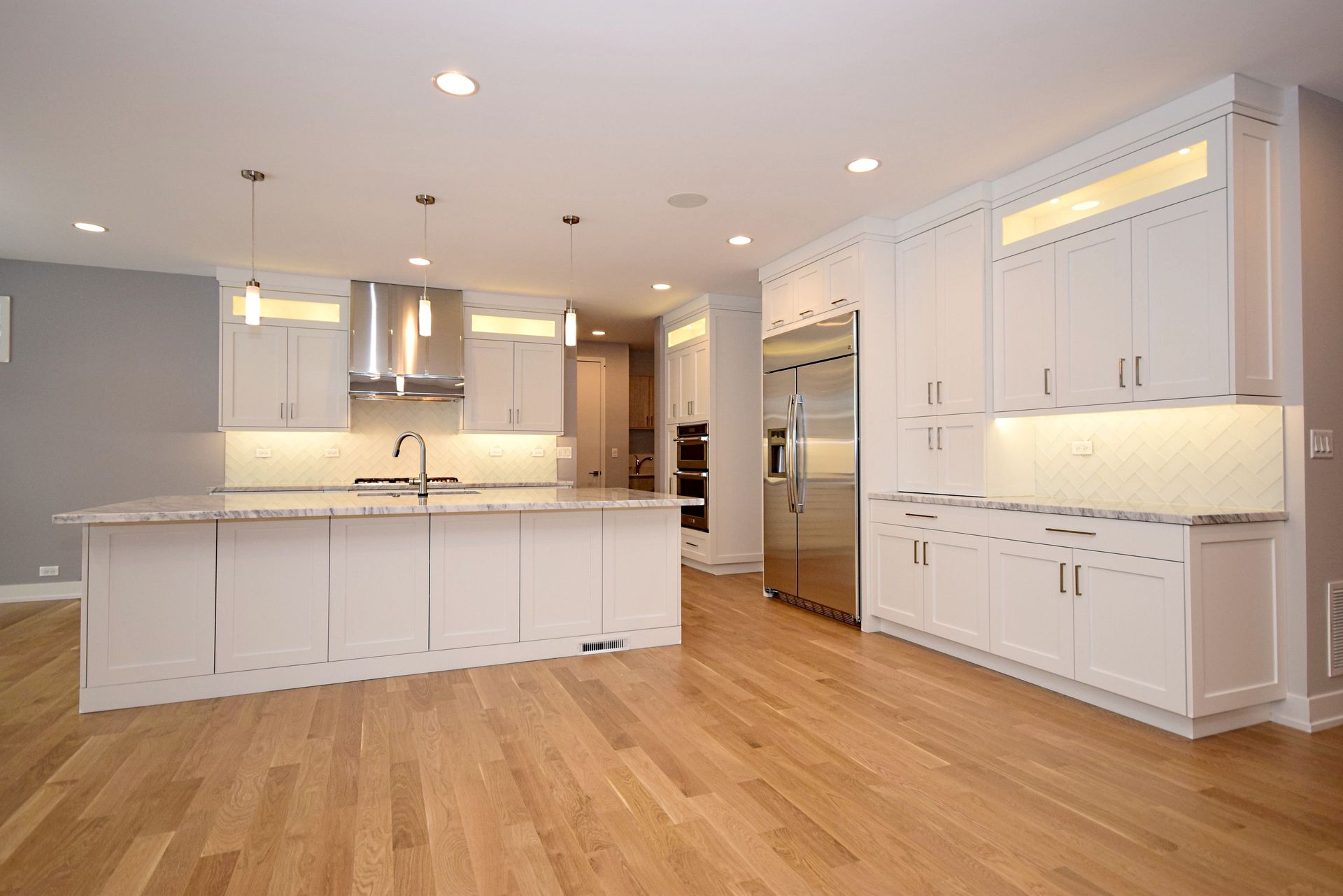 An empty kitchen with white cabinets and hardwood floors