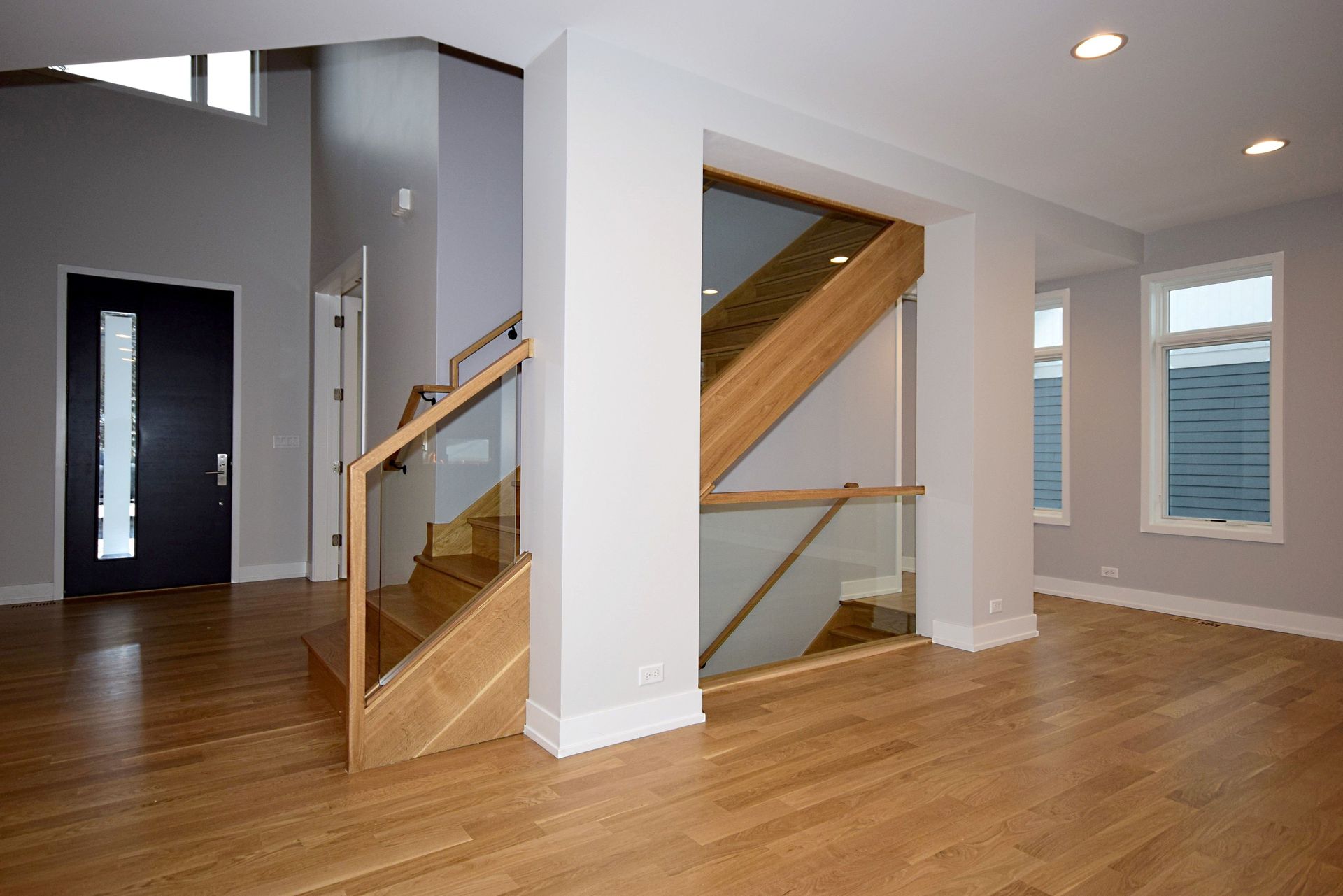 An empty room with a wooden staircase and a glass railing