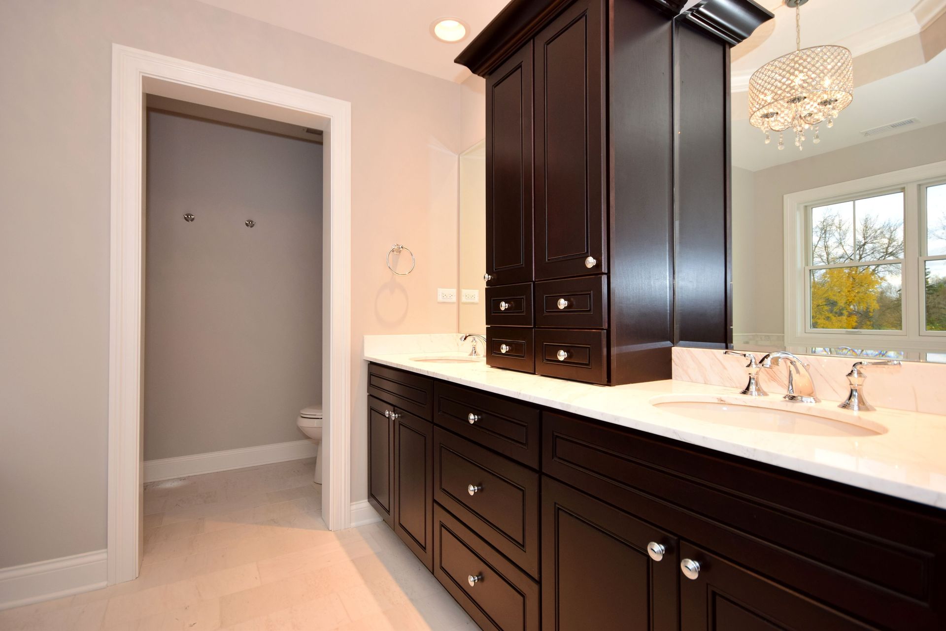 A bathroom with two sinks , a toilet and a mirror.