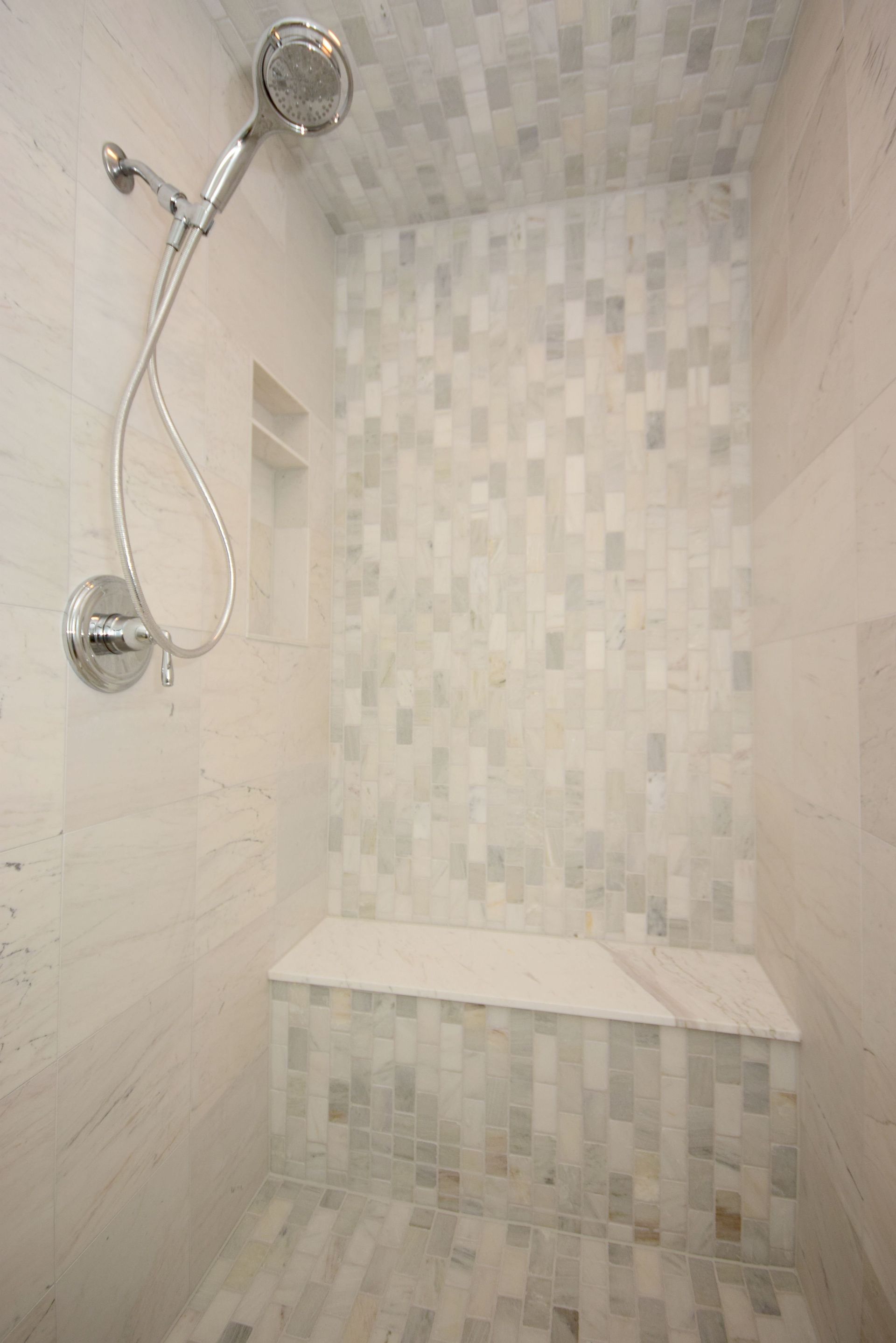 There is a shower with a bench and a shower head.