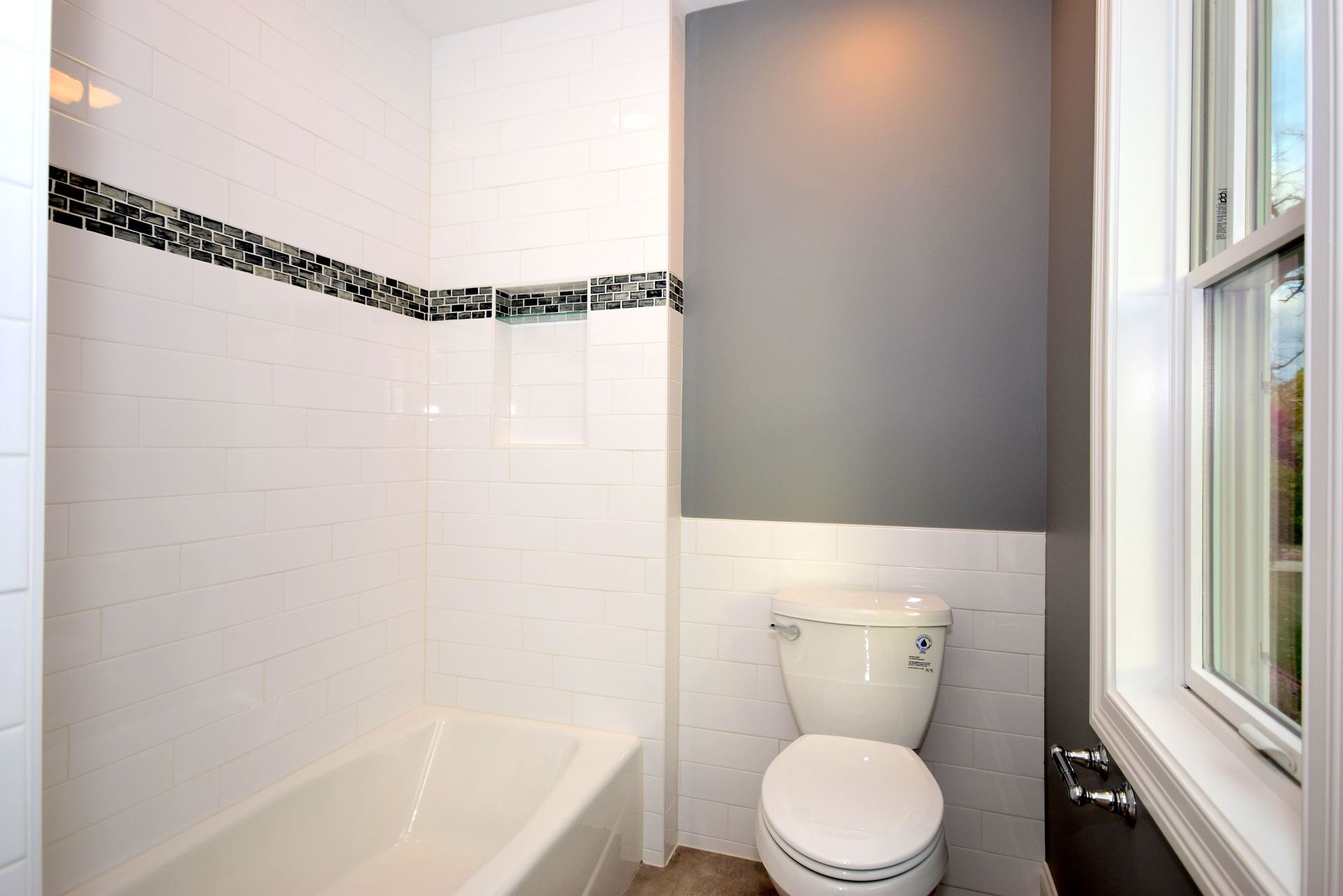 A bathroom with a toilet , tub and window