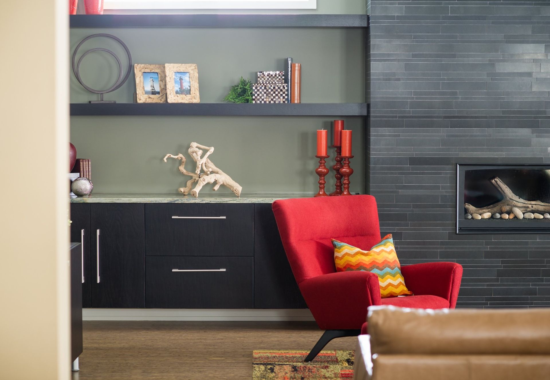 A living room with a red chair and a fireplace.