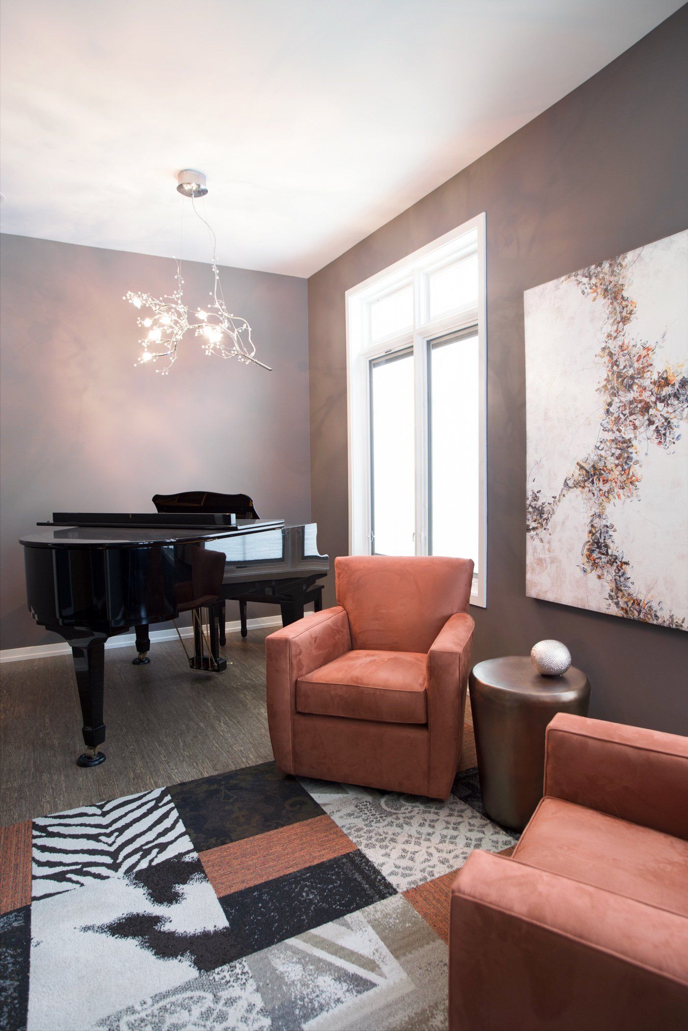 A living room with a piano , chairs , and a rug.