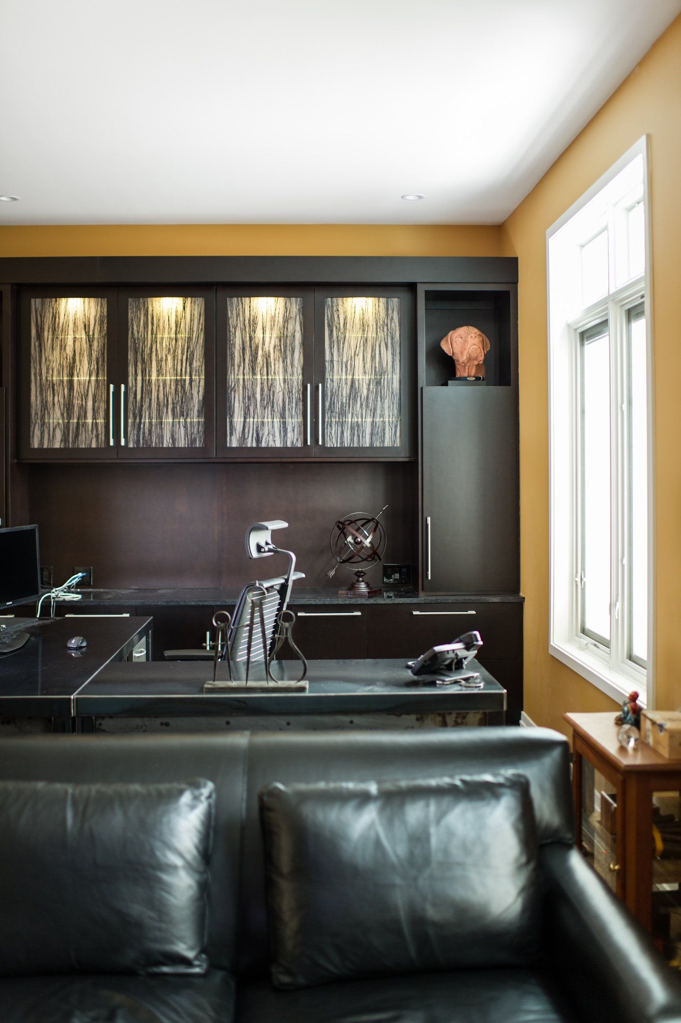 A living room with a black couch and a desk