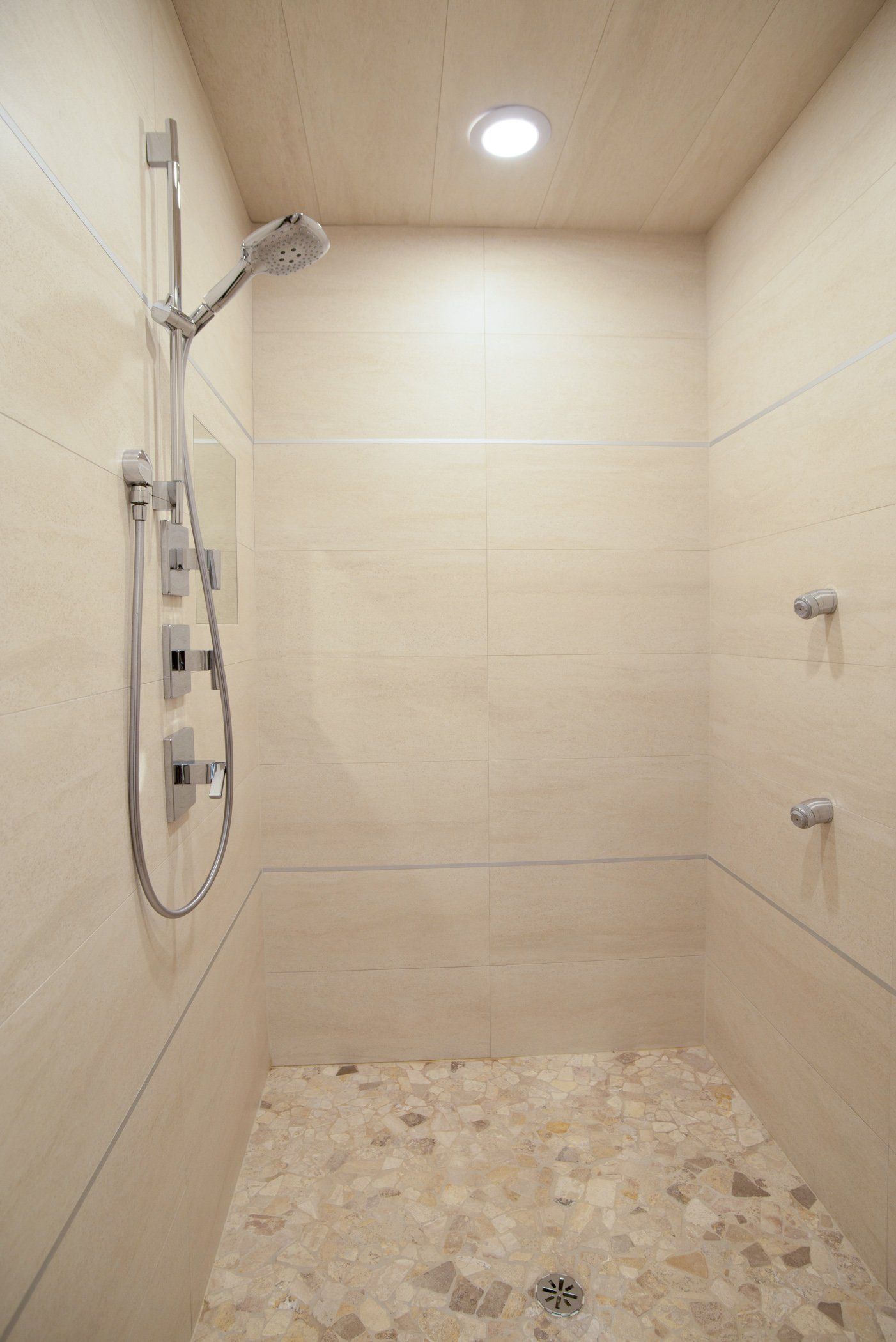 There is a shower with a tiled floor and a shower head.