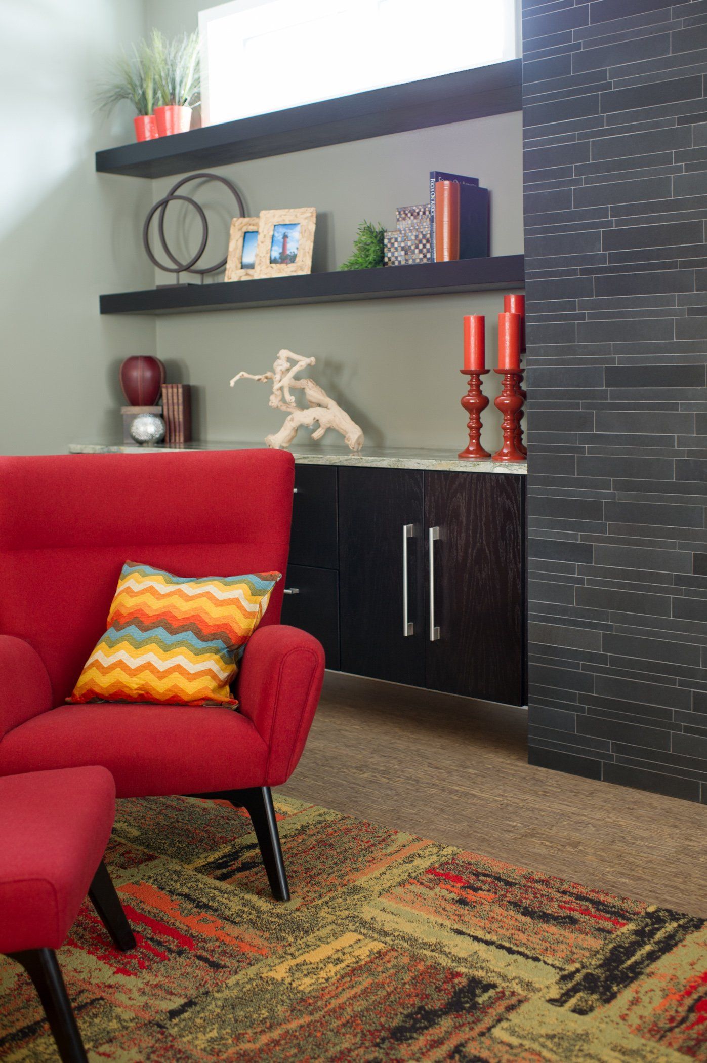 A living room with a red chair and a colorful rug.