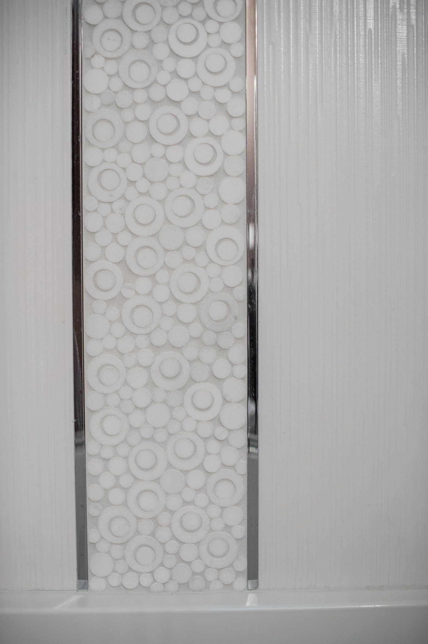 A white wall with a silver trim and a pattern on it.