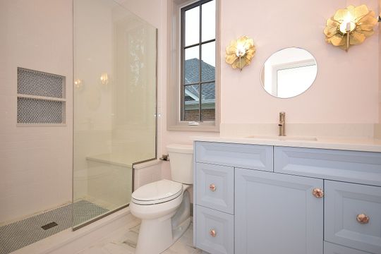 A bathroom with a toilet , sink , mirror and shower.