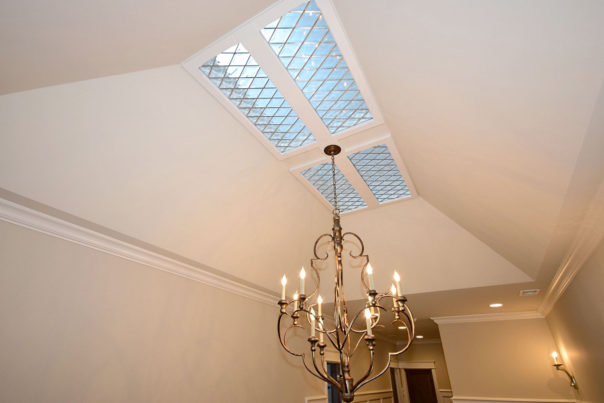 A chandelier is hanging from the ceiling in a room with a skylight.