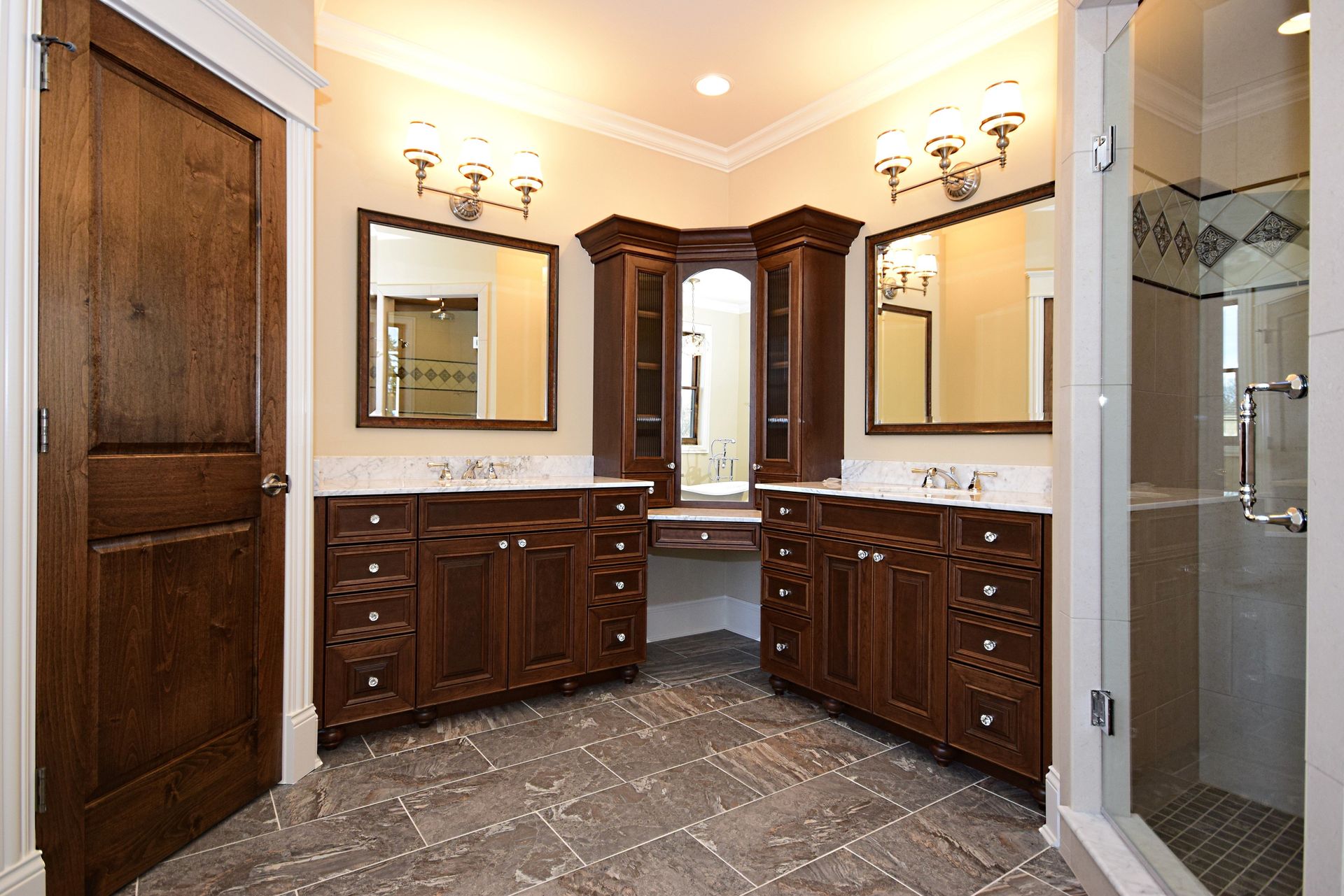 A bathroom with two sinks , two mirrors and a walk in shower.